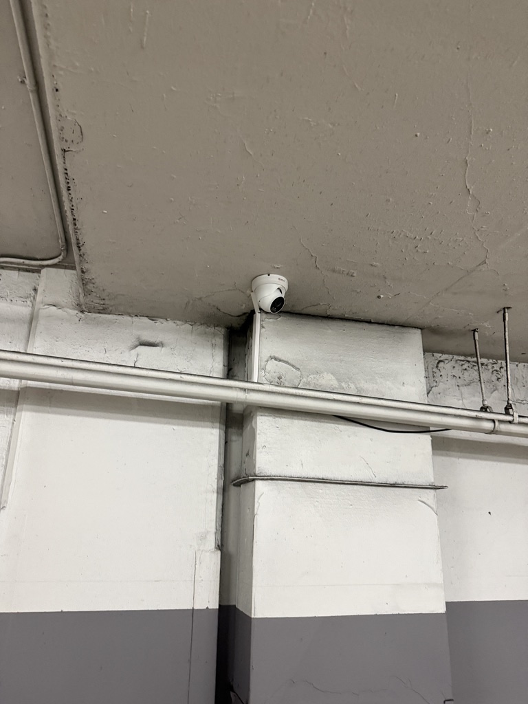Turret camera installed beside a concrete parking-garage column.